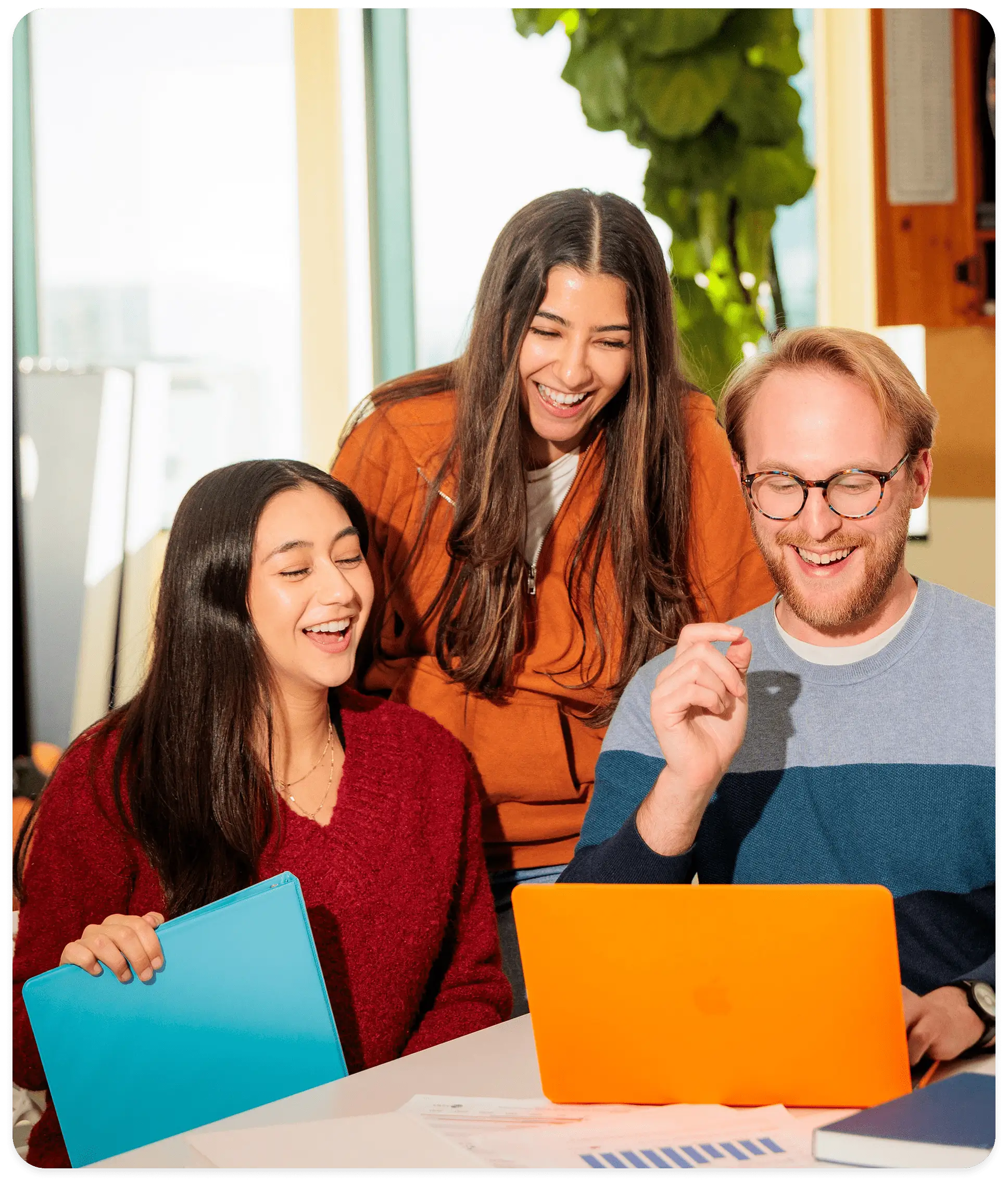 A group of individuals is gathered around a laptop, engaged in an evaluation